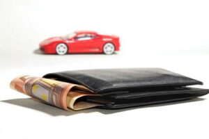 Zwarte portemonnee gevuld met geld door de private lease voordelen en op de achtergrond een rode sportauto