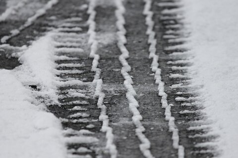 bandenspoor in de sneeuw op een asfaltweg