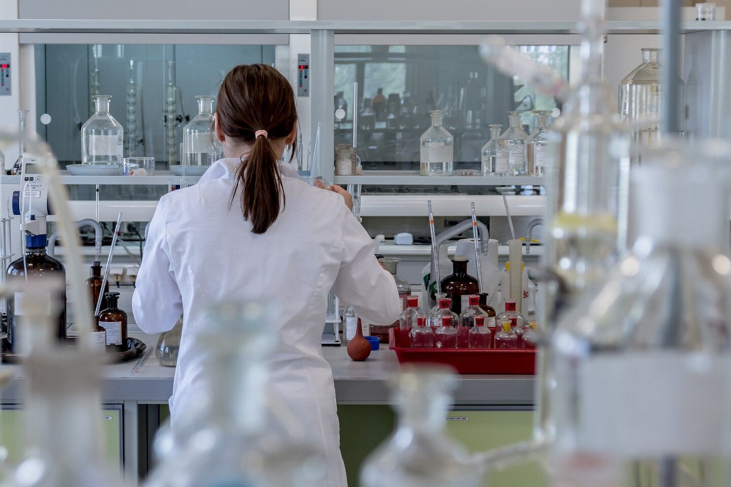 vrouw in een laboratorium met alleen verschillende glazen flessen naast haar