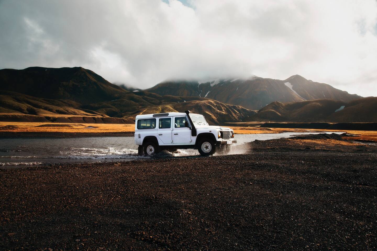een witte land rover defender in een open vlakte op IJsland